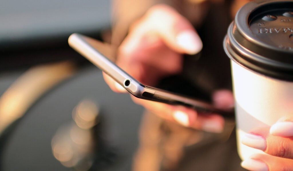 woman holding phone and coffee