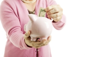 Closeup Of Woman Saving Money In A Piggy Bank White Background