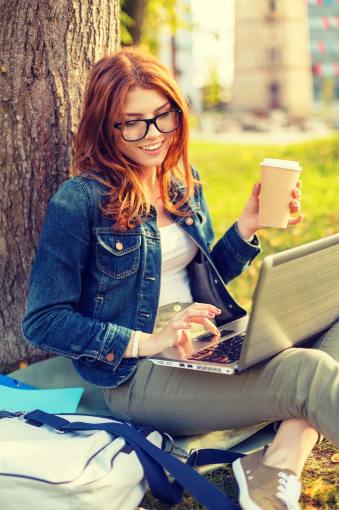 Education Technology And Internet Concept Smiling Redhead Teenager In Eyeglasses With Laptop Computer And Take Away Coffee Or Tea