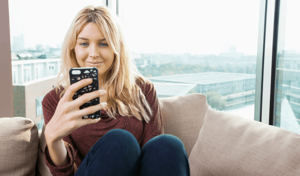woman smiling looking at phone on couch