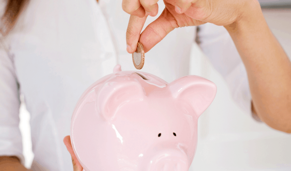 woman putting coin in pink piggy bank