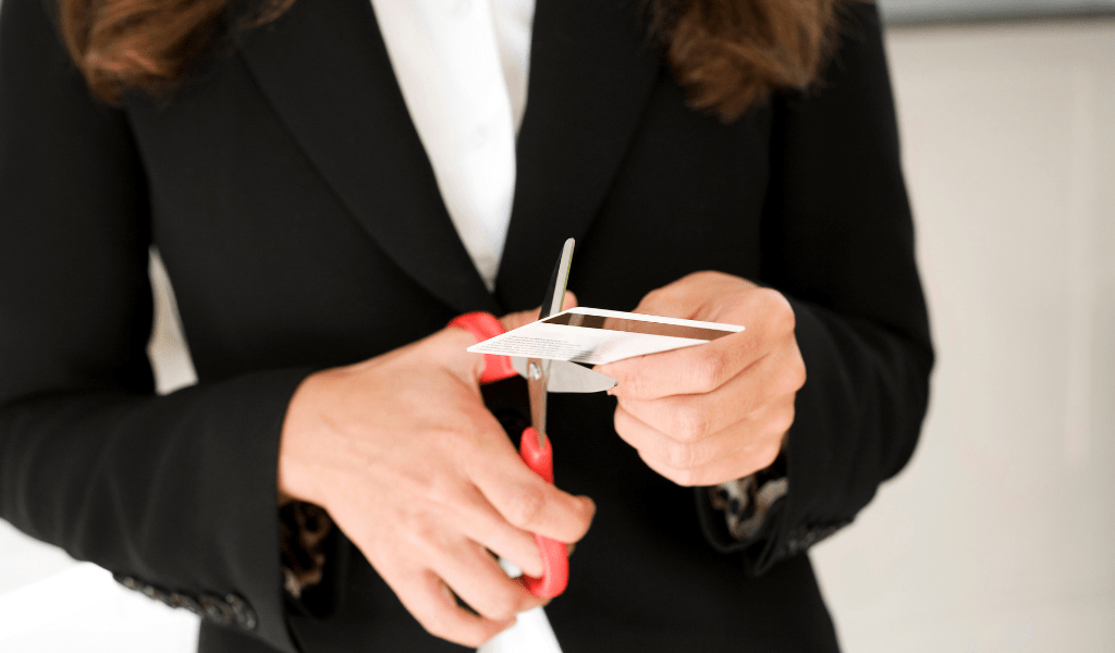 woman cutting card Managing your money in your 20s