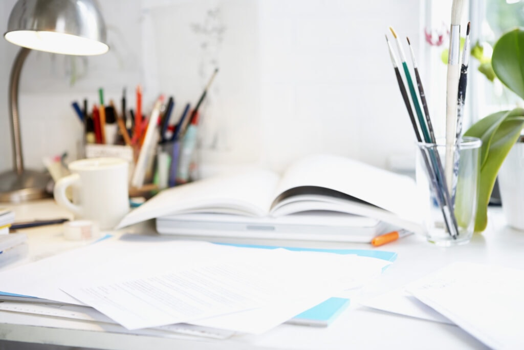 desk with books and paint brushes Managing your money in your 20s