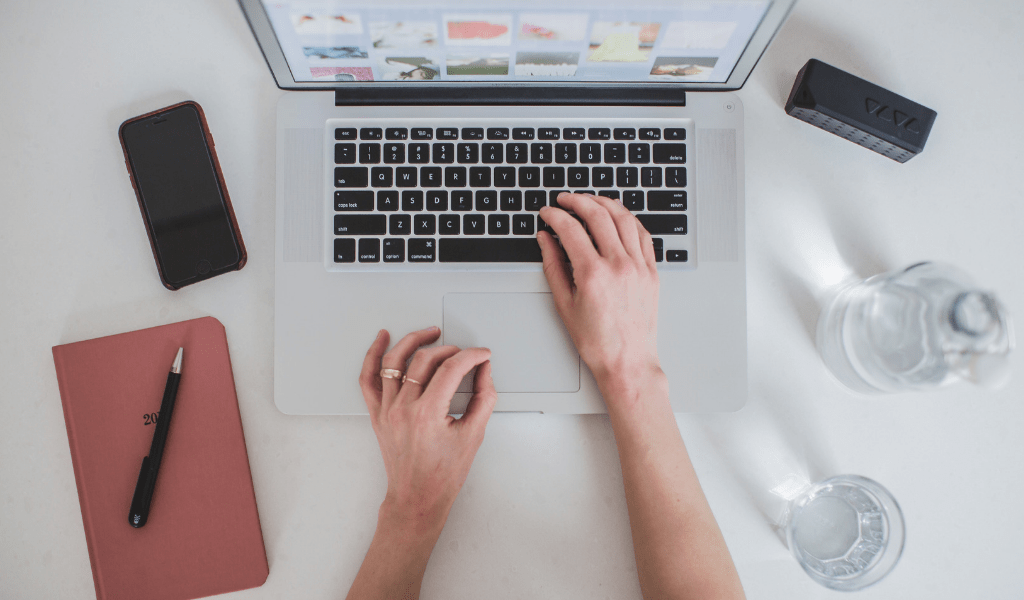 person earning money online on their computer with a planner and phone