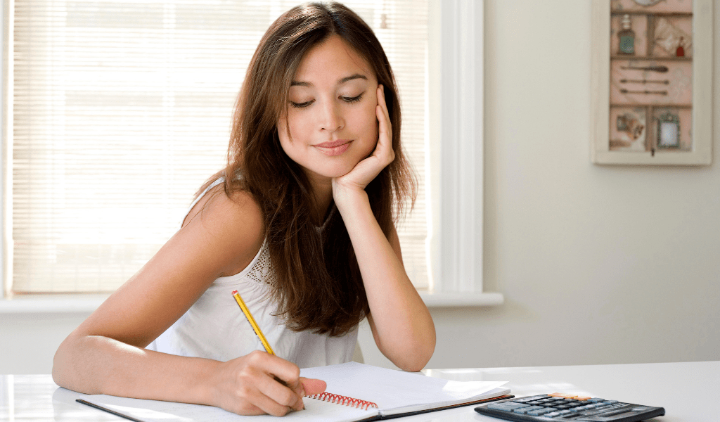 woman writing in notebook and calculator 