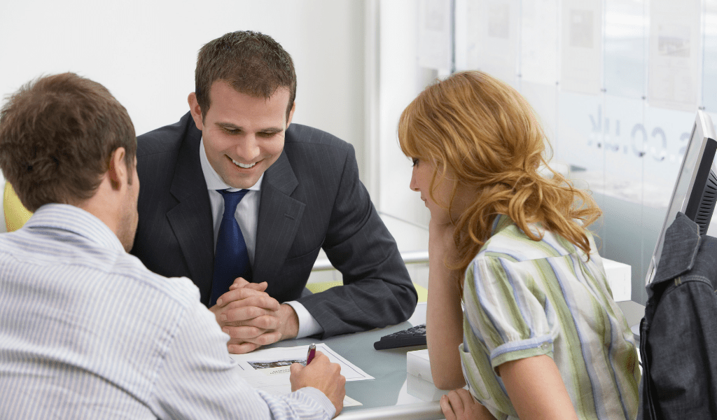 young couple at a bank talking with a young man at a desk