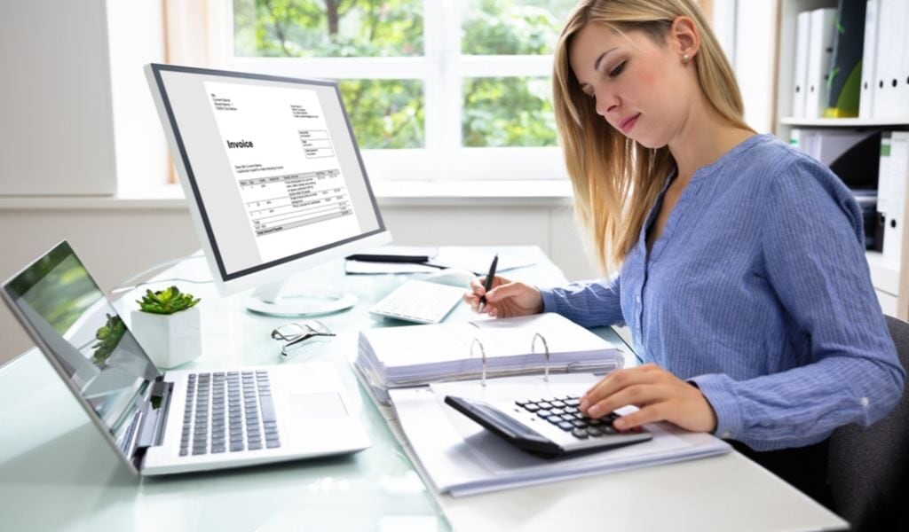 woman at desk looking at calculator