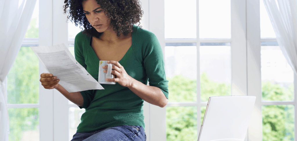 woman looking at collection notice while drinking coffee