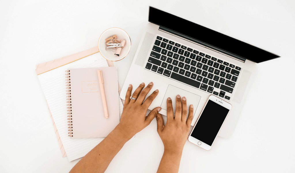 woman on computer with notebook and phone 