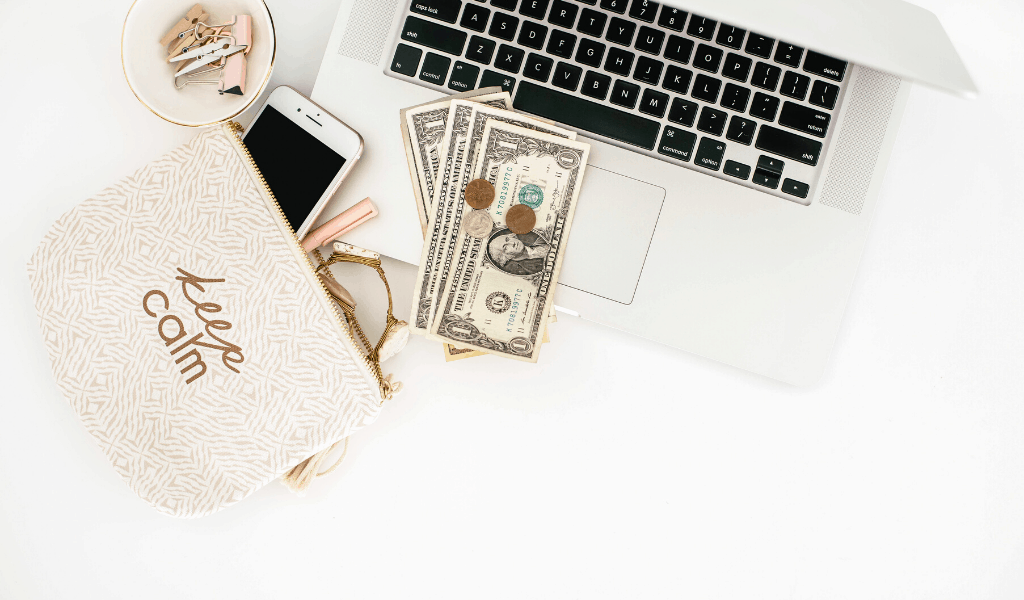 pocketbook with cash and laptop on desk