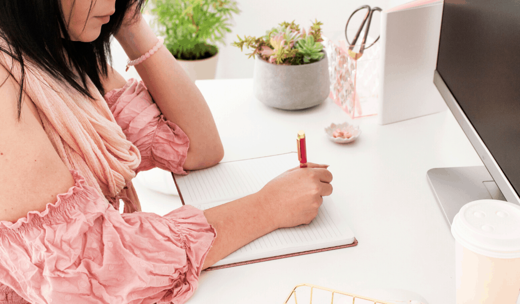 woman at a desk writing in a notebook