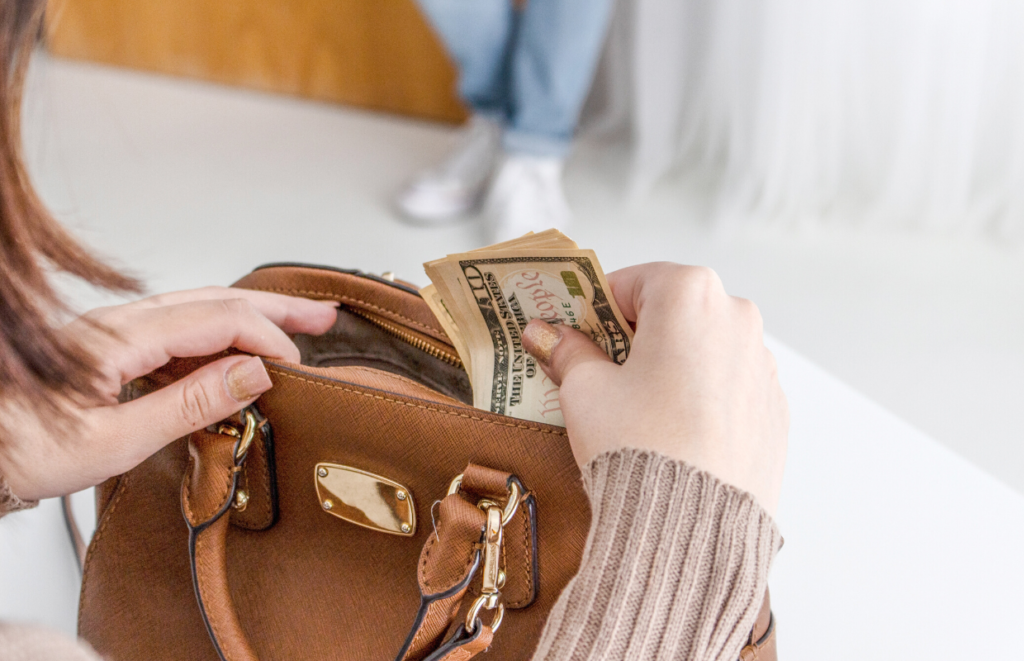 white female holding dollar bills in a brown purse