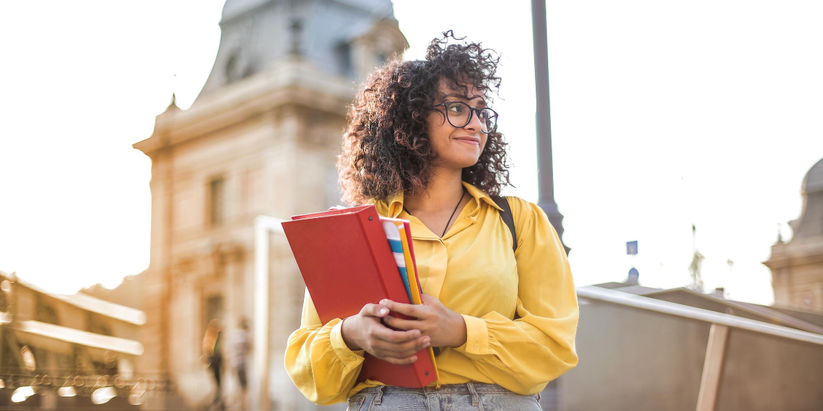 Young girl holding notebooks as she walks around her college campus