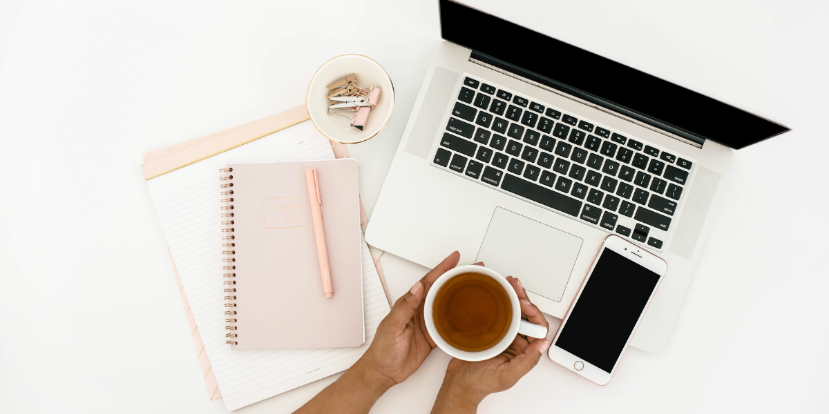 Women's hands holding a cup of tea at her desk