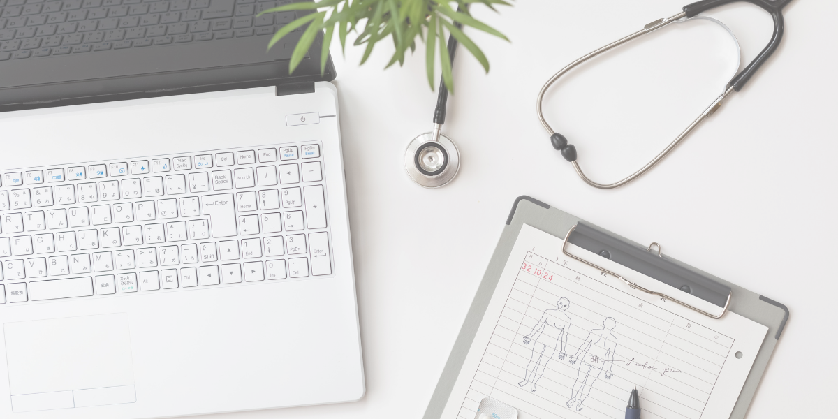 Computer sitting on desk with clipboard of medical notes and a stethoscope