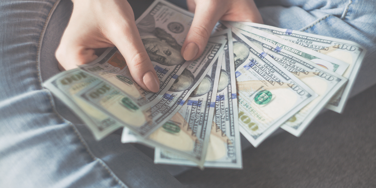 Female holding several hundred dollar bills