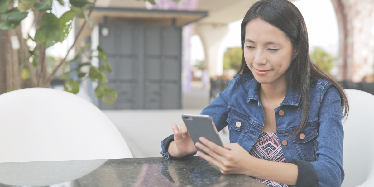 Female Sitting at a table outside scrolling on her cell phone