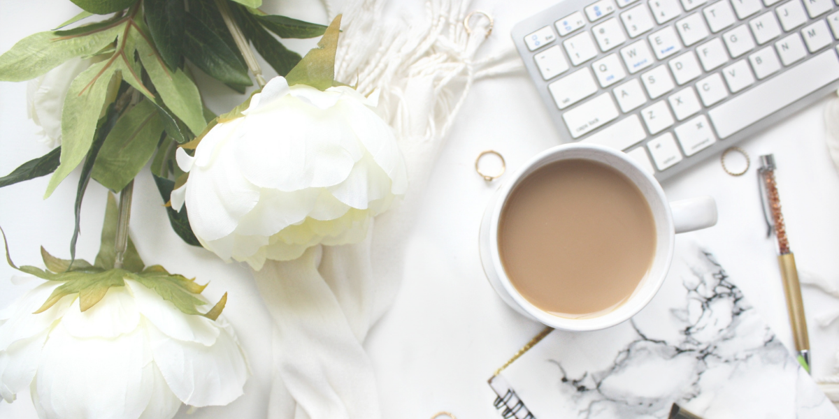 White flowers lying on deask with cup of coffee and a keyboard