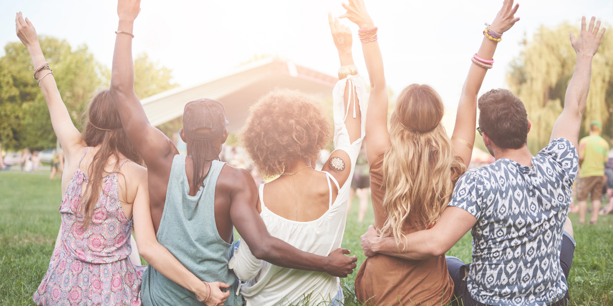 Group of friends sitting side by side in  a grassy area