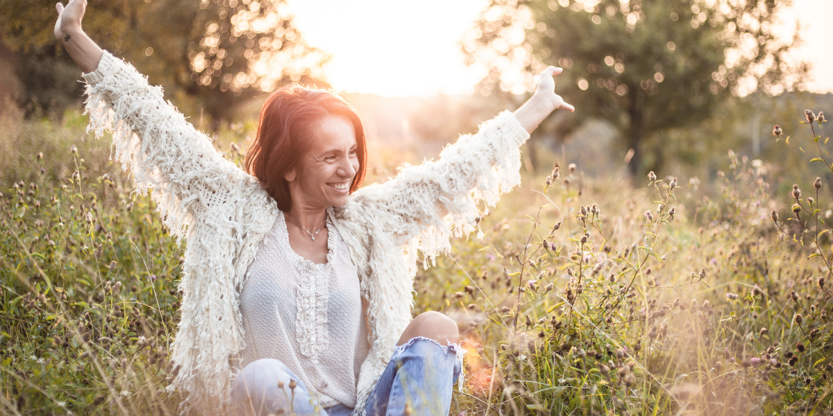 White female siting in a field with an overjoyed expression