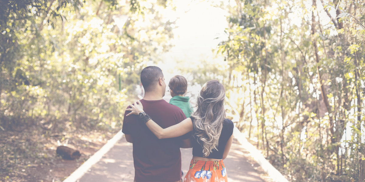 Father holding son with mother walking alongside them