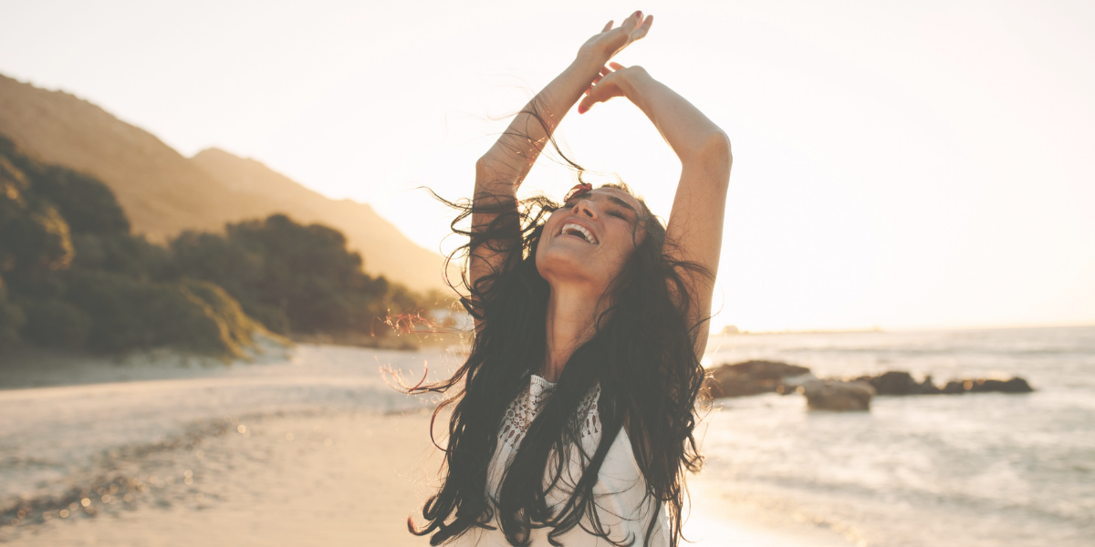 Female on the beach raising her hands in excitement