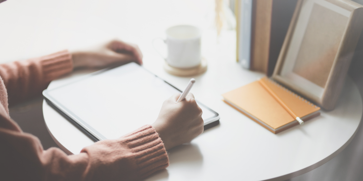 Female sitting at a small table working on her tablet