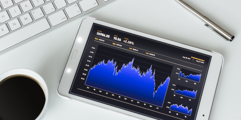 ipad on table by a keyboard with stock market image of investments made and earning money for paying off debt.