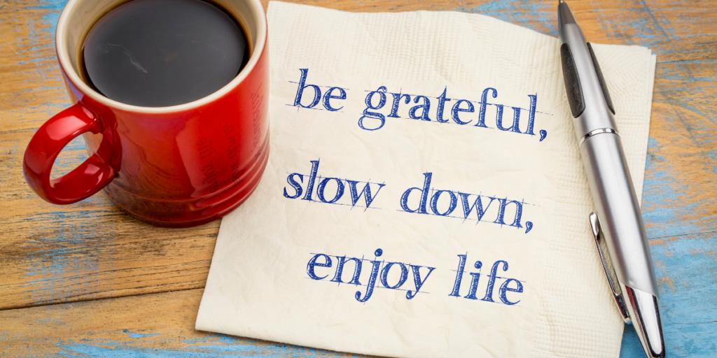 Words of encouragement to be grateful, slow down, enjoy life written on a napkin with a pen and a cup of coffee nearby to change ones money mindset and work towards securing a financial future. 