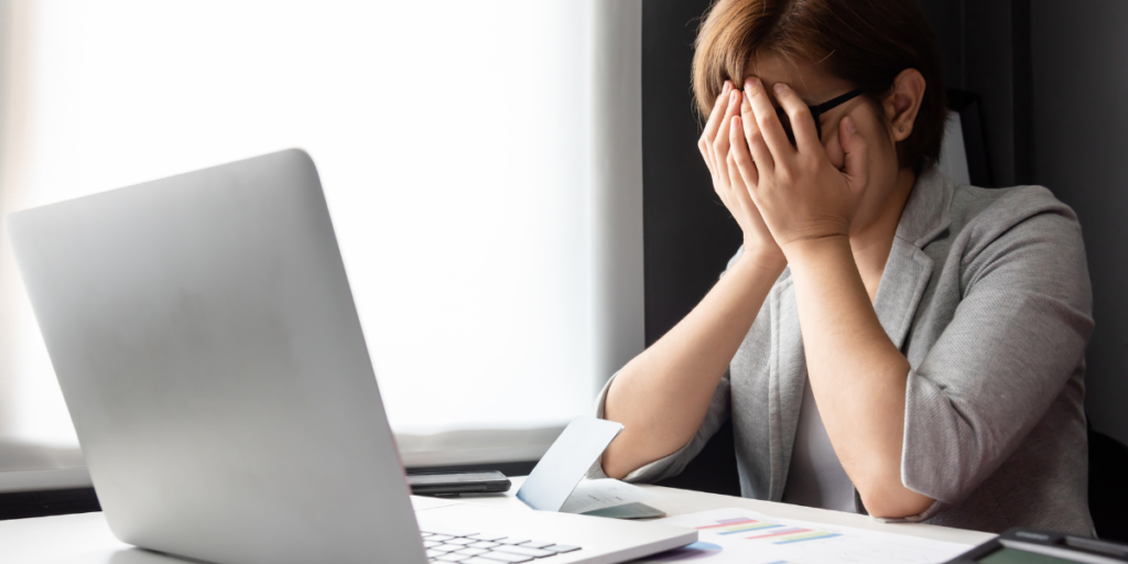 Lady sitting at table in front of laptop calculating debt to pay off so she can invest.