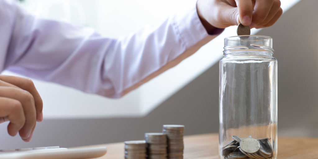 A guy putting money away into a jar because he has changed his money mindset and wants to secure his financial future. 