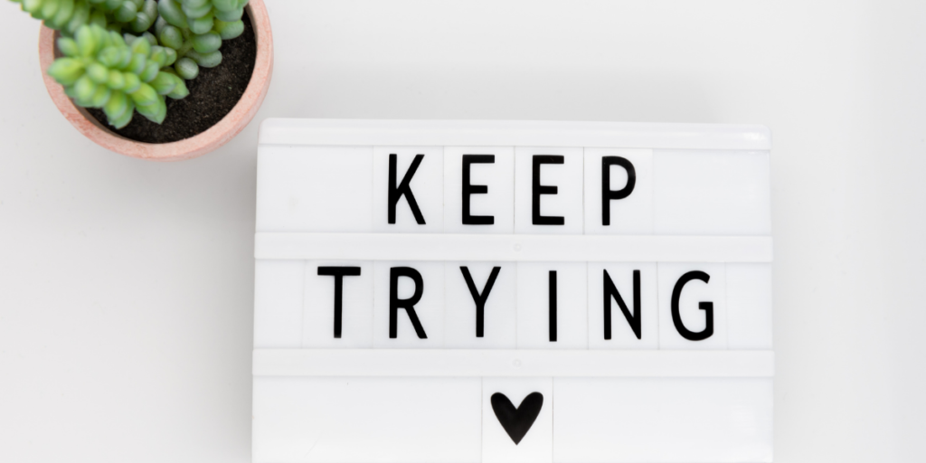 A white sign with a post of keep trying with a heart reminding you to change your money mindset to secure your financial future and if you fail just keep trying. 