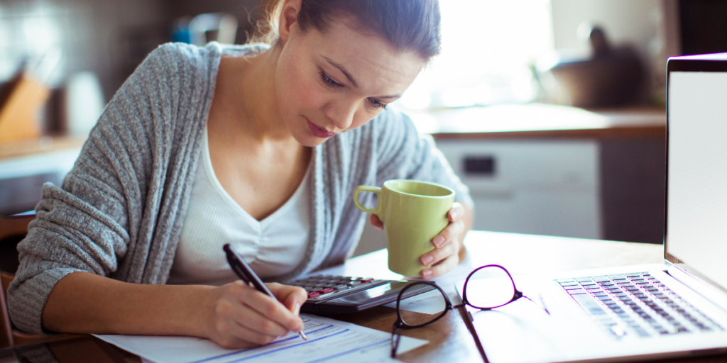 Lady at kitchen table working on budget to pay off minimum payments and investing.