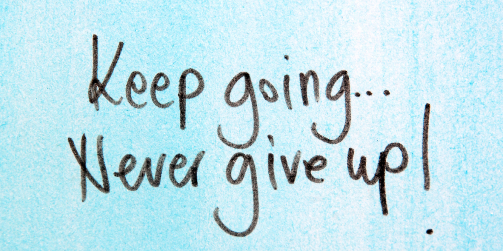 A light blue background with wording in black markerthat says "Keep going...Never give up!" on your financial goals. 