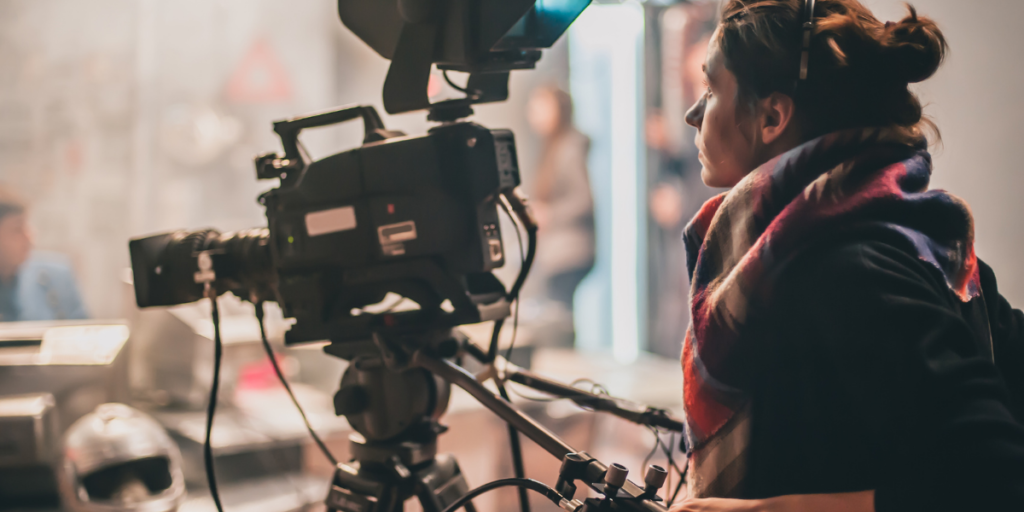 A female operating a movie camera helping to create free movies online for others to watch.