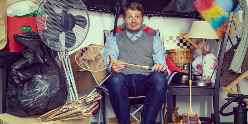 A male sitting in the middle of many of his belongings wondering how he can get back to sticking to a budget. 