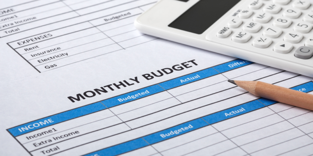 A monthly budget spreadsheet with a pencil and a calculator being used to stick to a budget. 