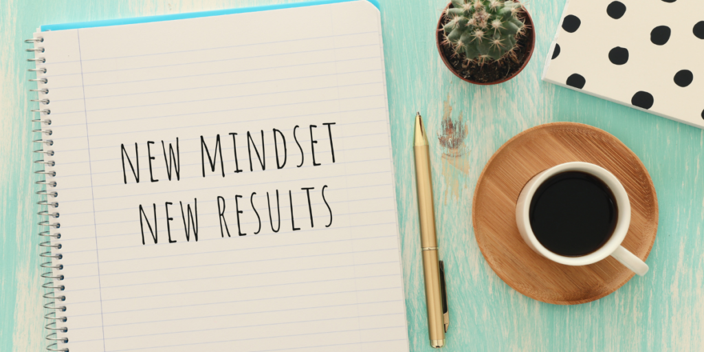 A notebook on a table with a pen and a cup of coffee with the financial goals wording "New Mindset New Results" written on the page.