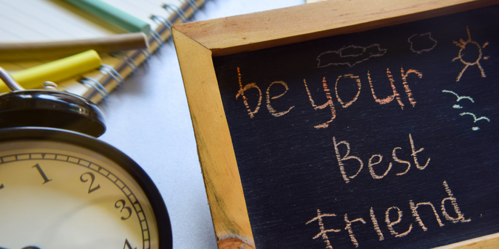 A clock sitting beside a chalkboard sign with "Be your best friend" written on it as a cue to stick to your budget.