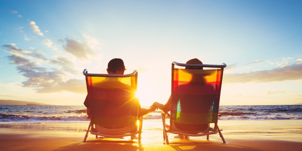 A couple sitting on the beach together watching the sunset and enjoying their road to becoming a millionaire. 