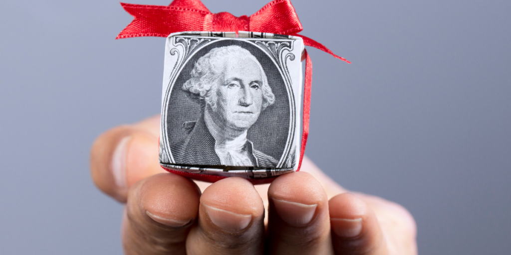 A dollar bill folded into the shape of a gift box with a red bow tied on it.  Money can be a gift when you stick to your budget. 