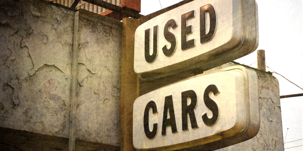 A used cars sign for a car lot to help people buy used cars to help become a millionaire.