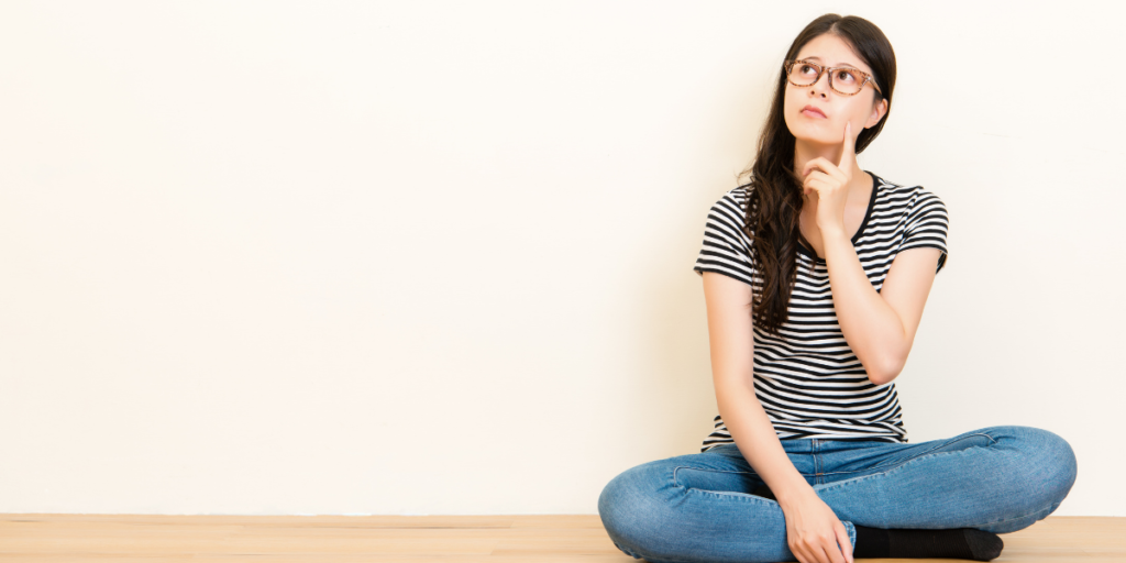 A woman sitting on the floor thinking about how she can stick to her budget. 