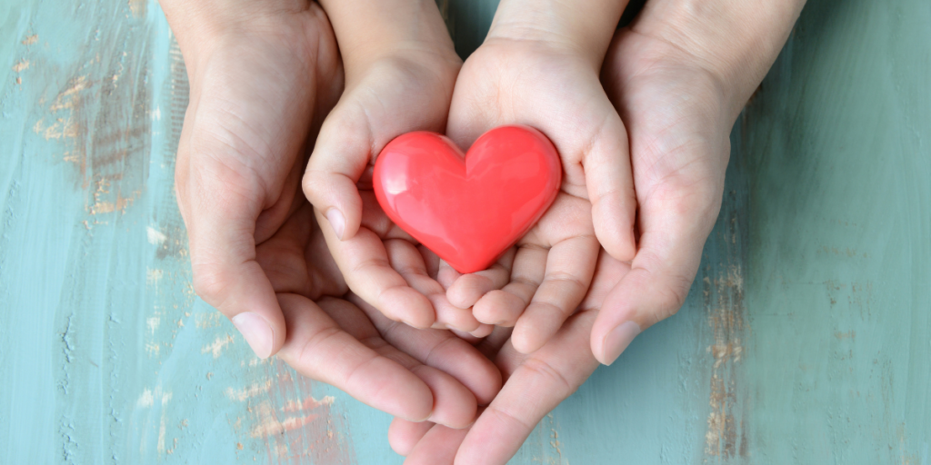A family of three holding a red heart in their 
