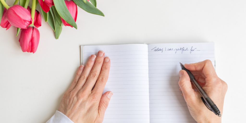 A person writing what they are grateful for in a journal to help them stay motivated. 