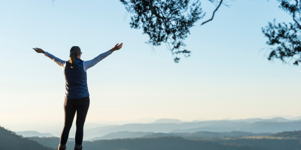 A woman enjoying the view from the top of a mountain because the sky is the limit when you stay motivated. 