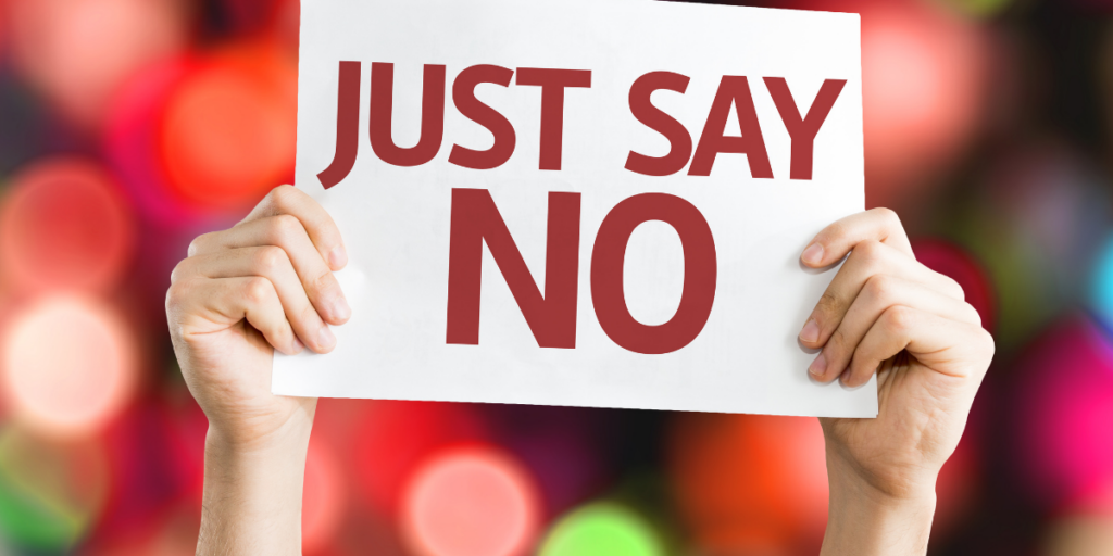 A person holding a sign that says Just Say No to taking on too many commitments in an effort to stay motivated. 