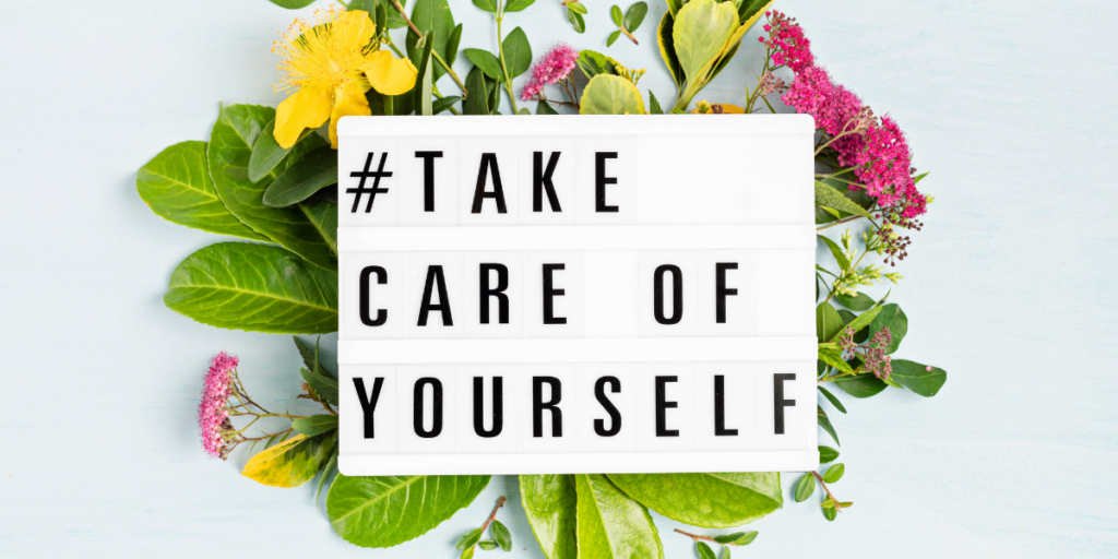 You have to take care of yourself in order to stay motivated. #Take careof yourself on a sign laying on top of a bed of flowers. 