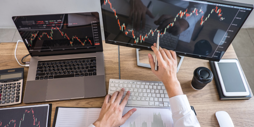 A guy reviewing the money market and his investment values at his desk on his computer. 