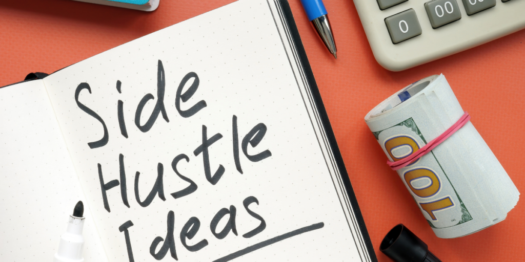 Side Hustle Ideas written on a page of a notebook beside a roll of 100 dollar bills, a pen and a calculator.